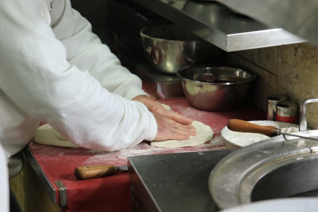 Pizzaiolo wyrabia ciasto na pizzę
