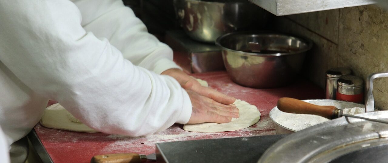 Pizzaiolo wyrabia ciasto na pizzę